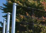 Tensioned overhead cable supports cage — no side poles or overhead structure to cause ball ricochet and no structure to snag or tear netting