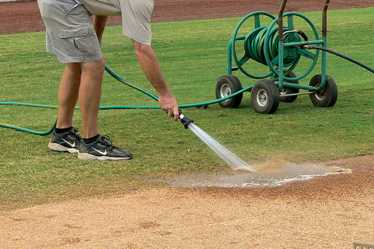 Man watering infield soil